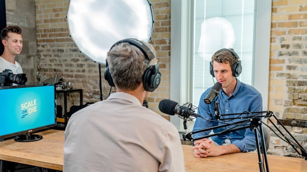 Podcast guests speaking on camera with automatic speaker framing and word-by-word animated captions visible — Photo by Austin Distel on Unsplash